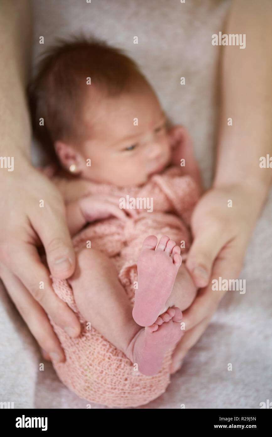 Neugeborene Füße close-up auf Eltern Hände Hintergrund Stockfoto