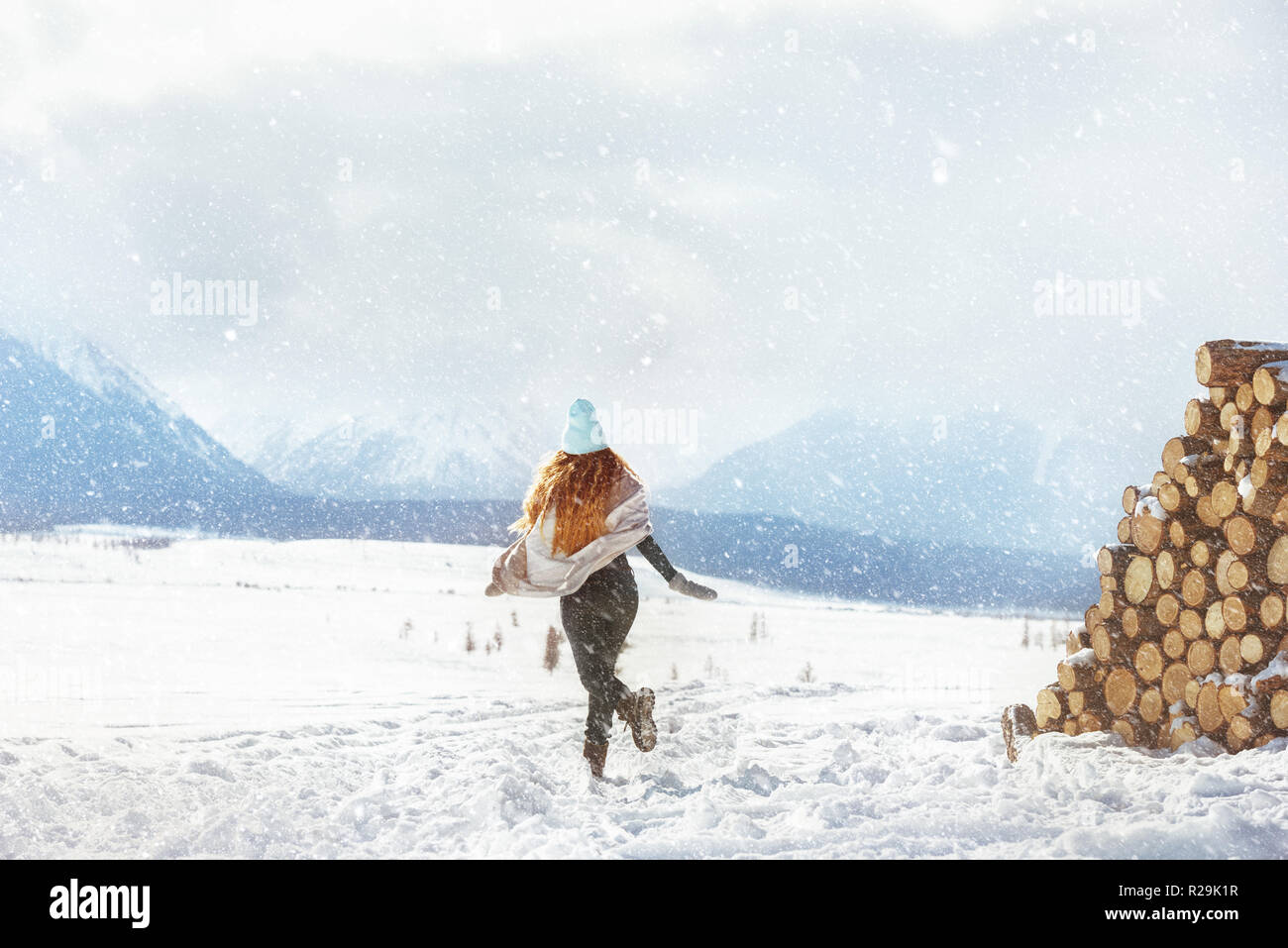 Glückliche junge Mädchen läuft auf den ersten Schnee in den Bergen Stockfoto