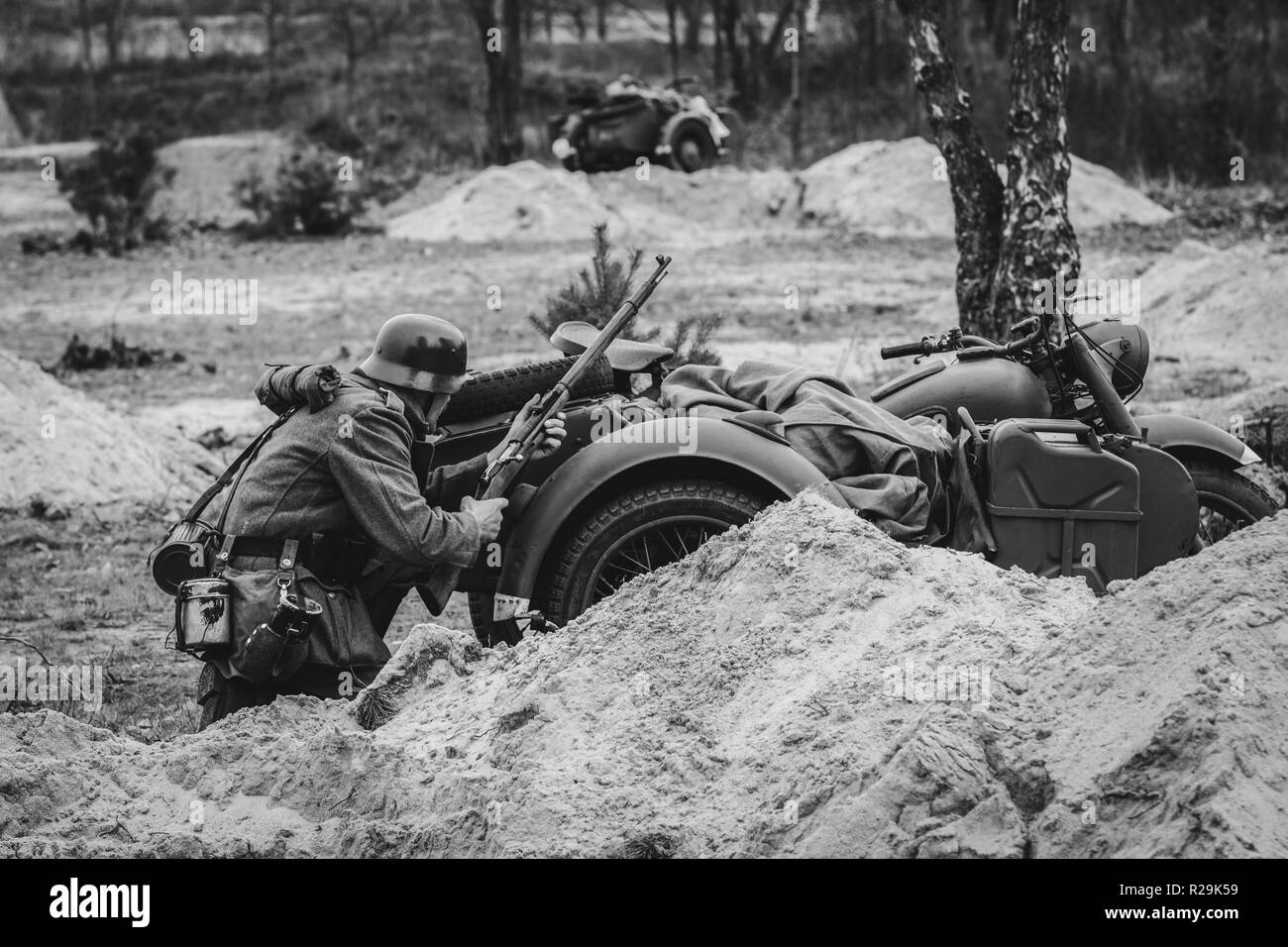 Deutscher Soldat der Wehrmacht Infanterie für den Schutz eines Motorrad während einer Schlacht mit einem Gewehr, Weltkrieg II. Schwarz und Weiß Foto Stockfoto