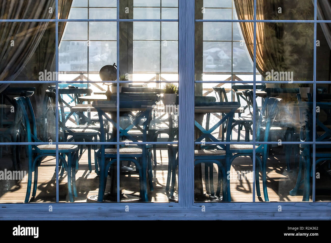 Innenraum eines Sommer Cafe hinter einer Glasfassade bei Sonnenuntergang im Sonnenlicht Reflexionen Stockfoto