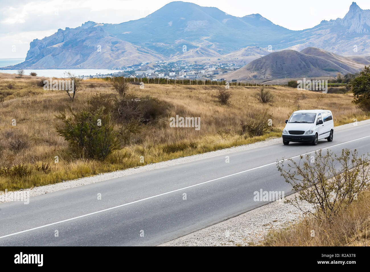 Minivan bewegt sich auf einer Landstraße in einer bergigen Gegend in der Nähe des Sees Stockfoto