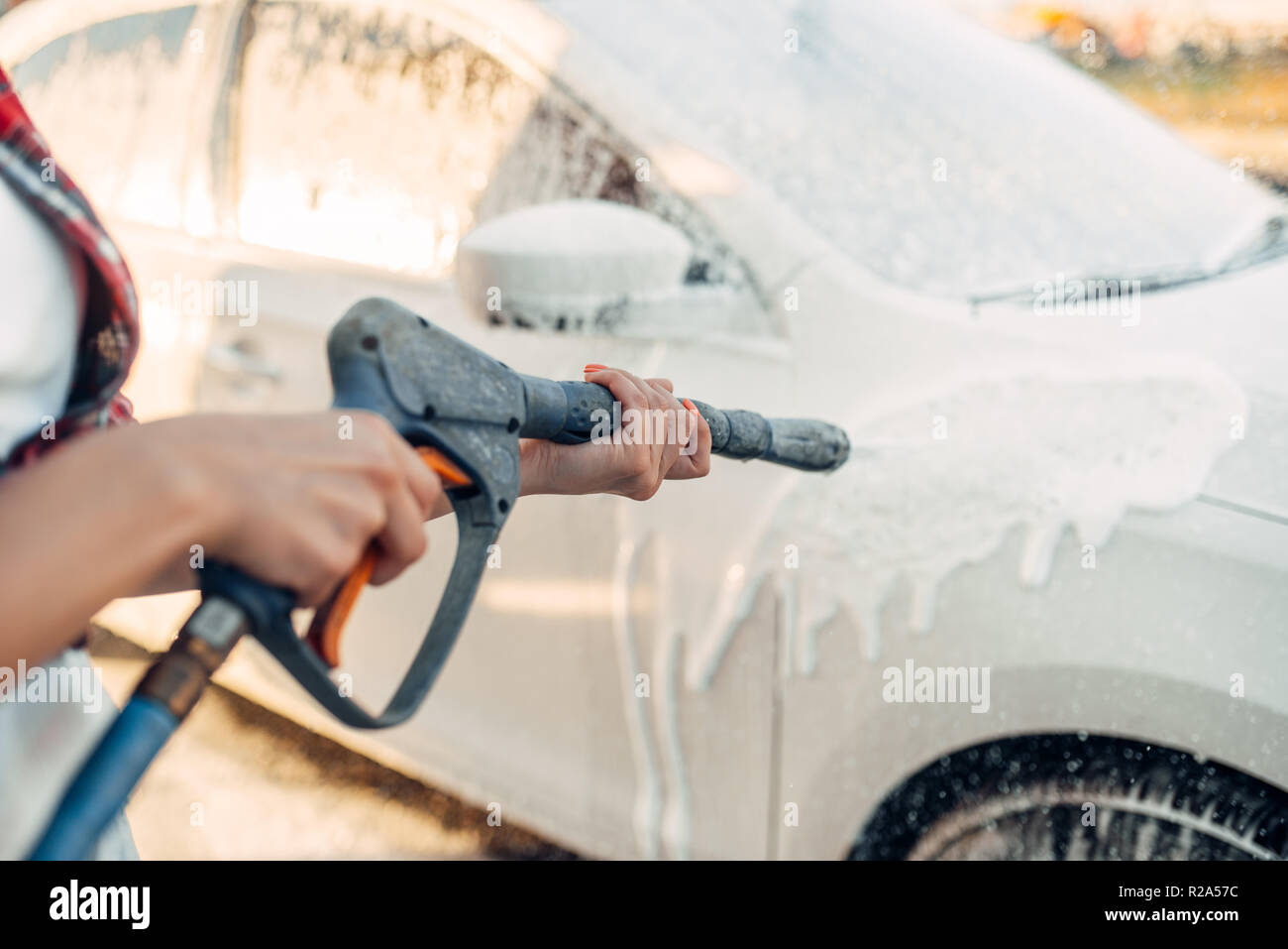 Weibliche Person Abwaschen der Schaum aus dem Auto. Junge Frau auf Self-service-Auto waschen. Outdoor Fahrzeug Reinigung bei Sommer Tag Stockfoto