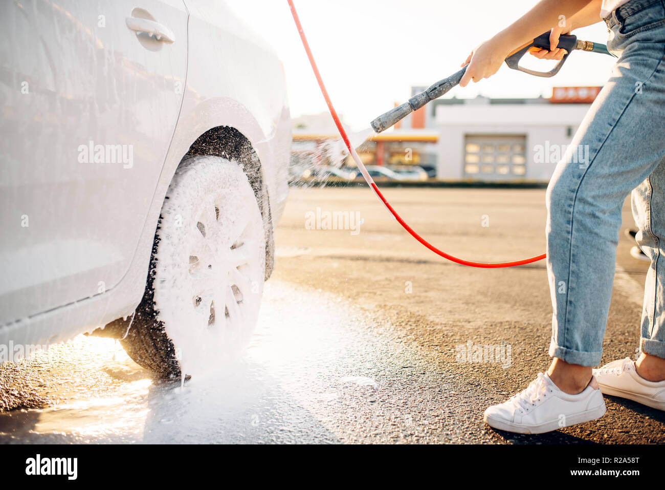 Foto zum Thema Ein kleines Mädchen, das ein Auto mit einem Schlauch wäscht  – Bild zu Hochdruckreinigung auf Unsplash