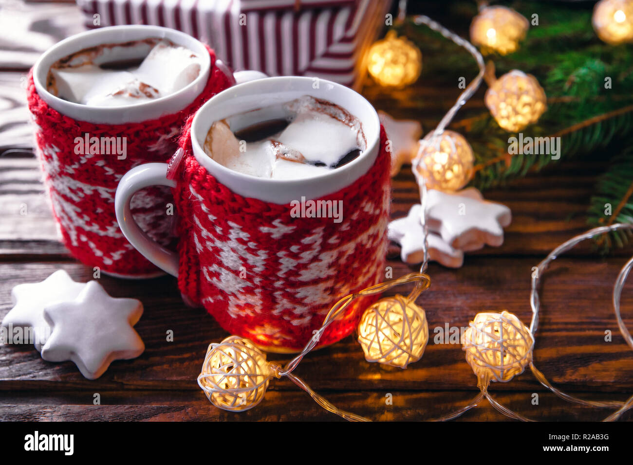Heiße Schokolade mit Marshmallows und Keksen auf Weihnachtsschmuck Hintergrund. Garland und Tanne gemütliche Atmosphäre schaffen. Stockfoto