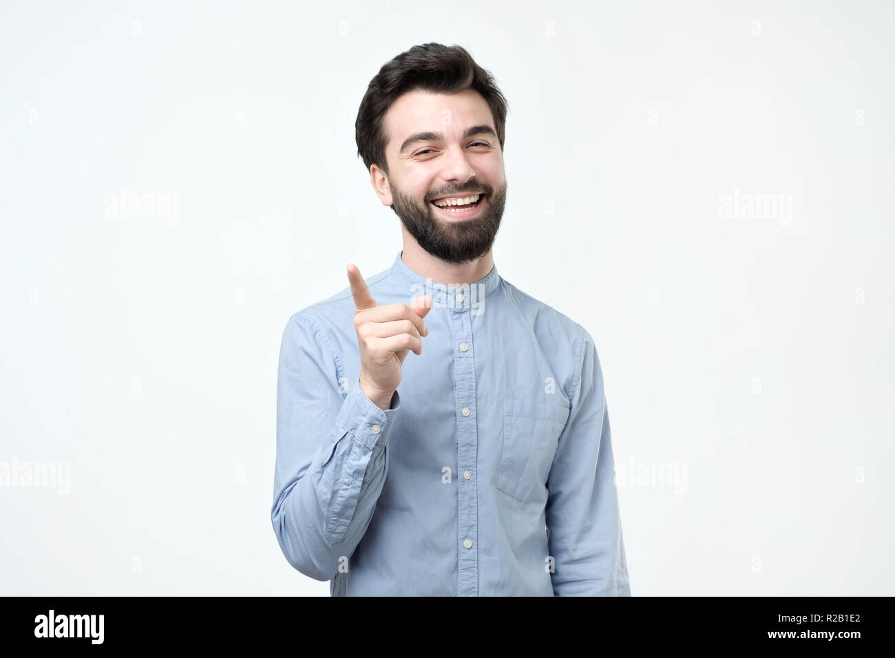 Happy positive bärtigen Hispanic Mann im blauen Hemd seinen Zeigefinger nach oben gekleidet Stockfoto