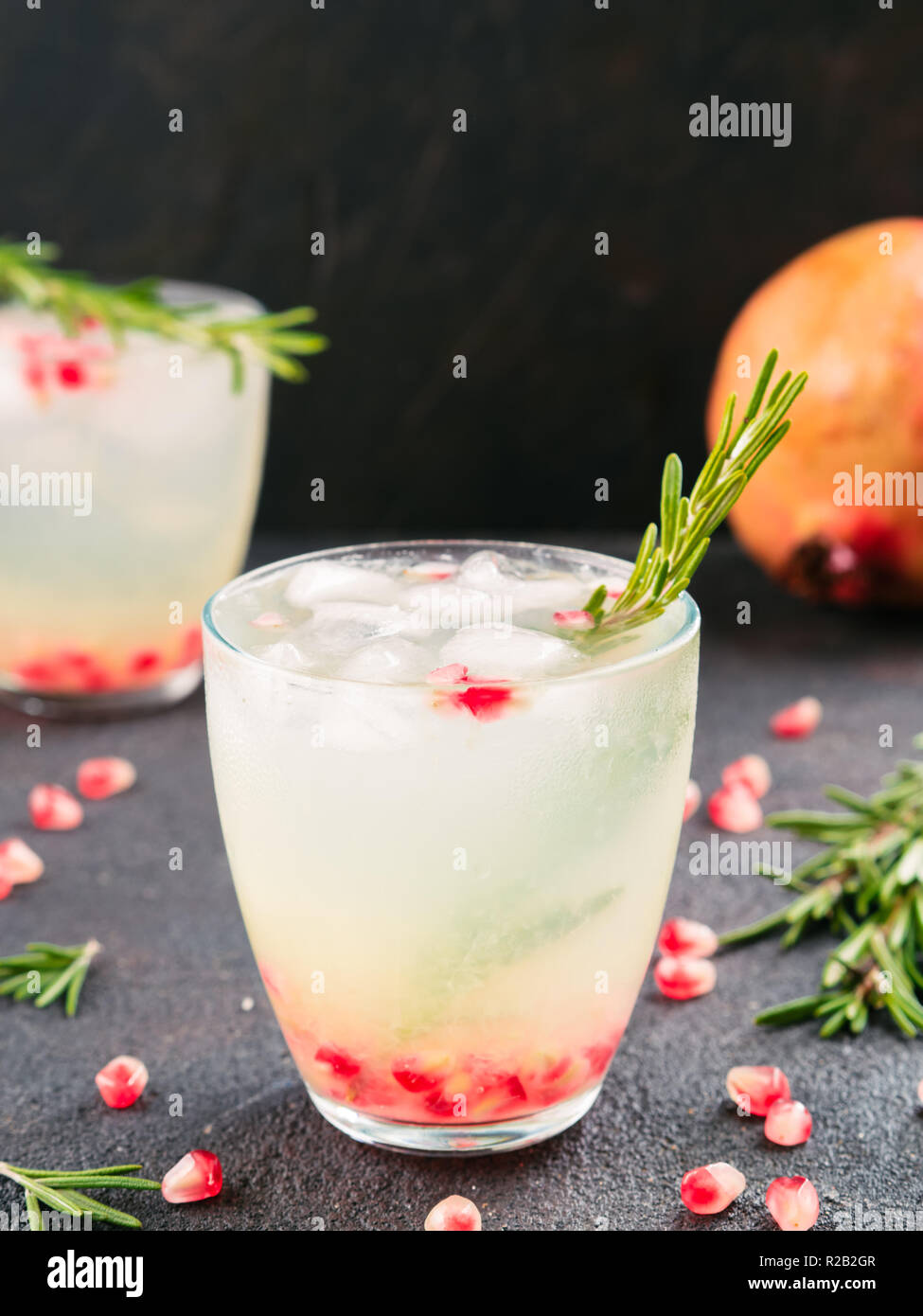 Herbst und Winter cocktails Idee - weiße Sangria mit Rosmarin, pomegrante und Zitronensaft und Zutaten auf schwarzem Zement Hintergrund. Stockfoto