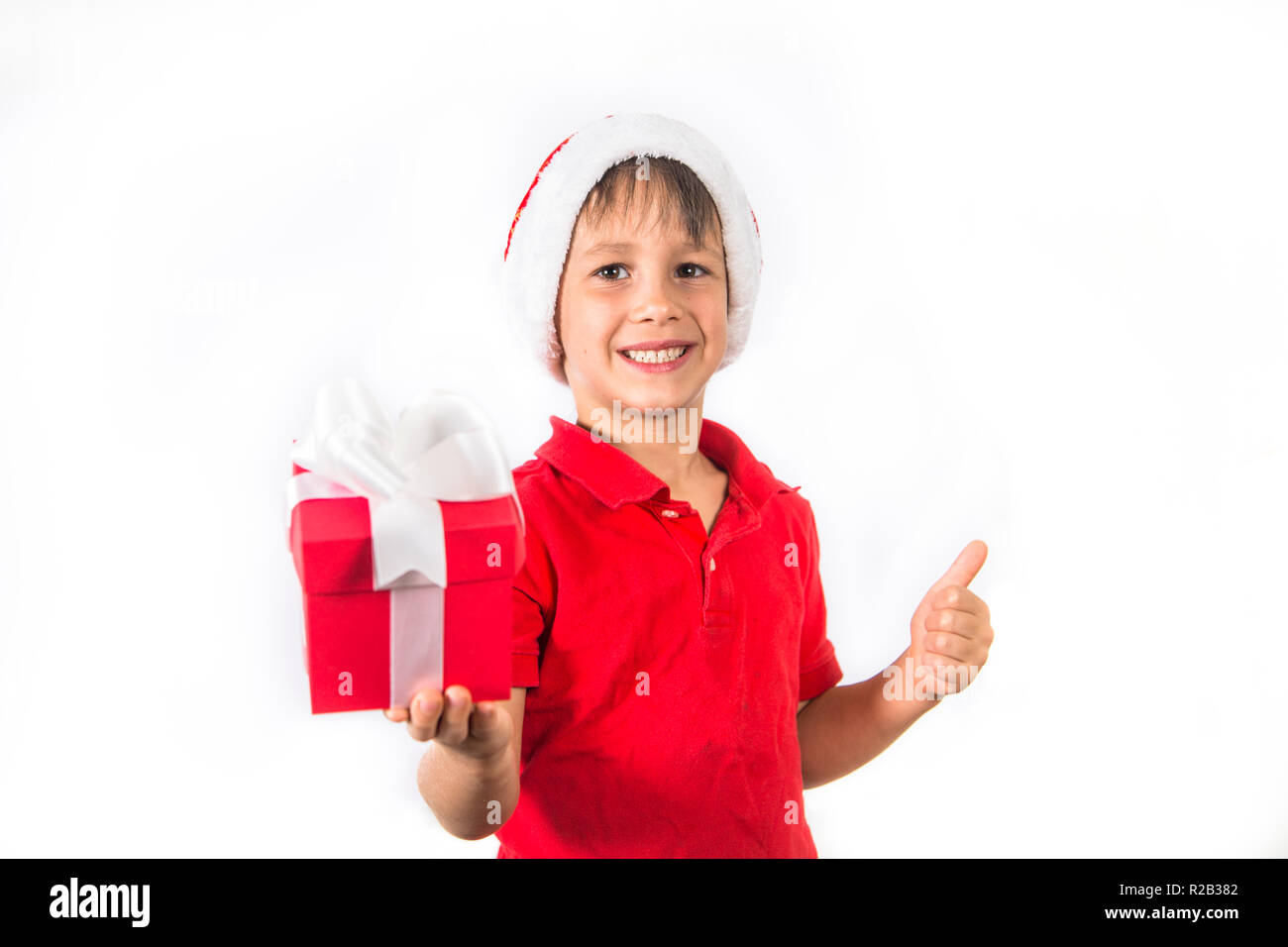 Kind Junge in Weihnachten Santa Hat und Red vorhanden Box auf Weiß. Stockfoto