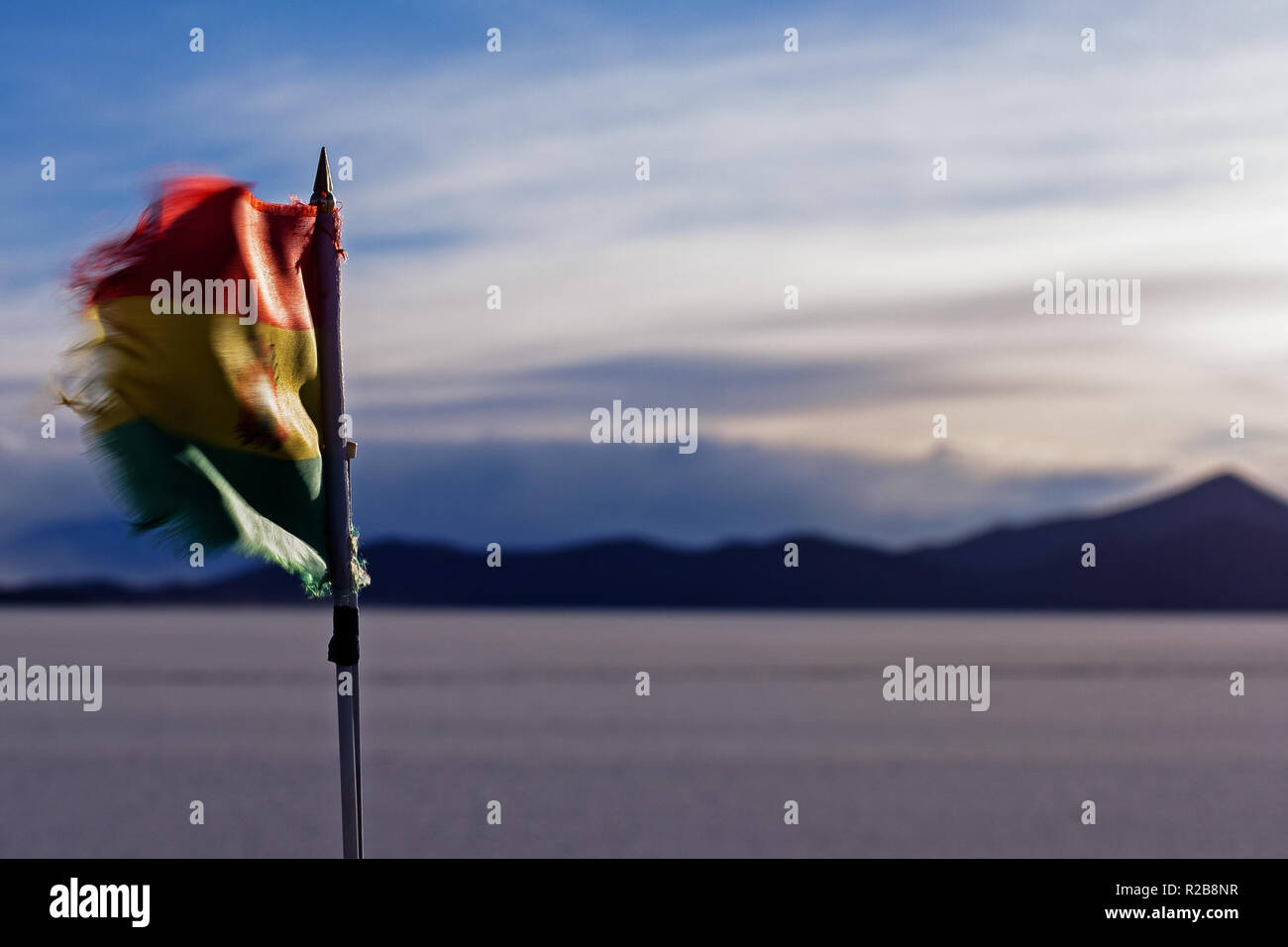 Wehende Flagge Boliviens bei Sonnenuntergang in der Salar de Uyuni Stockfoto