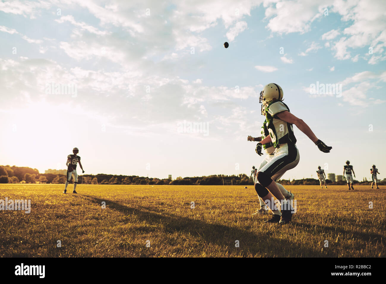 American Football Spieler laufen ein Pass während Team praktische Übungen auf einem Fußballfeld zu am Nachmittag fangen Stockfoto