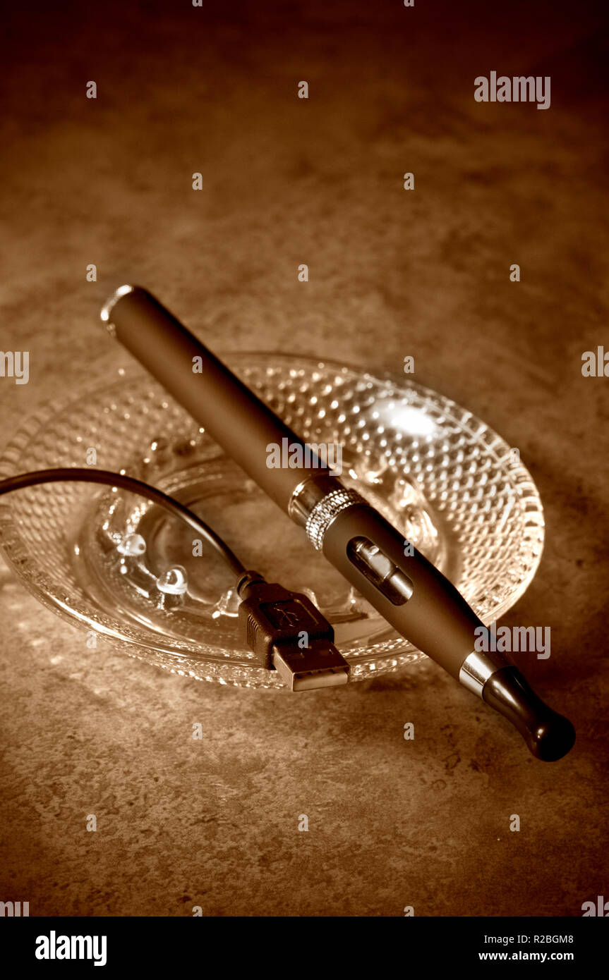 Sepia getont Elektronische Zigarette mit A/C Adapter und Aschenbecher auf dem Tisch Stockfoto
