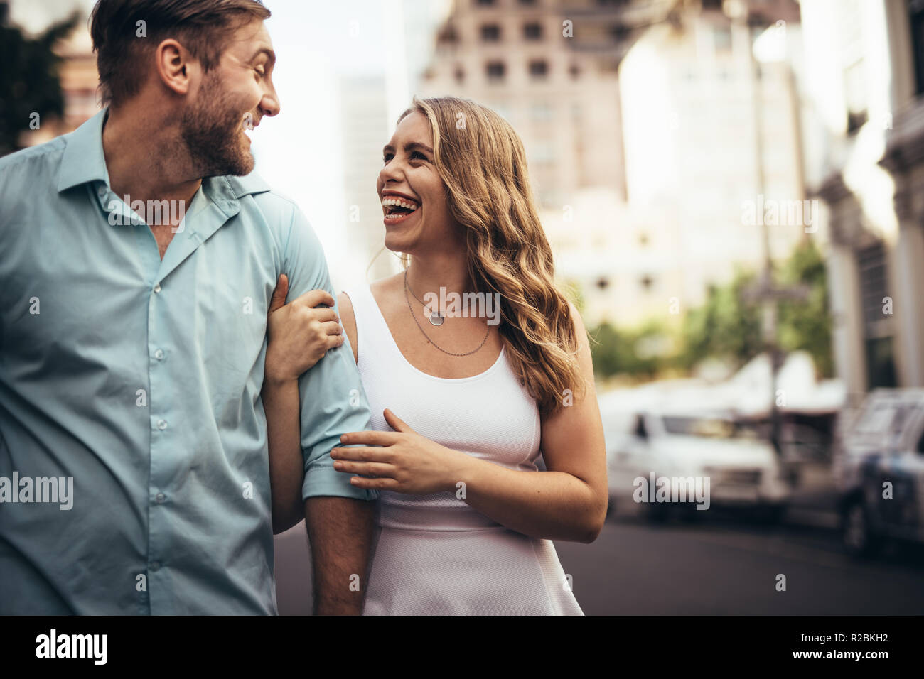 Freundliche Paar auf der Straße der Stadt lachen und sich an der Suche. Frau mit ihrem Partner beim Gehen auf die Straße. Stockfoto