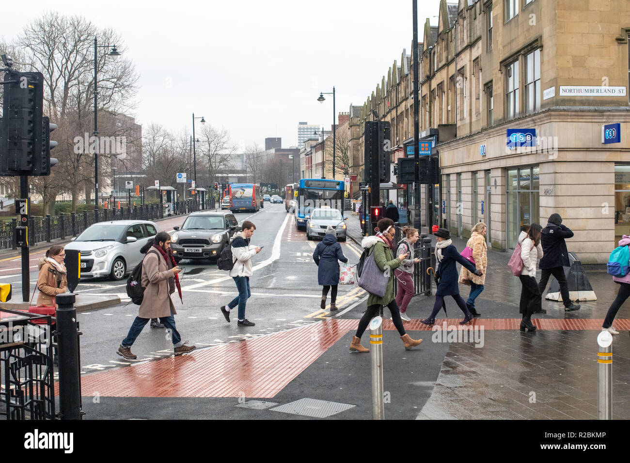 Newcastle upon Tyne/England - 10. Januar 2018: Newcastle Menschen zu Fuß über die Straße auf Handys Stockfoto