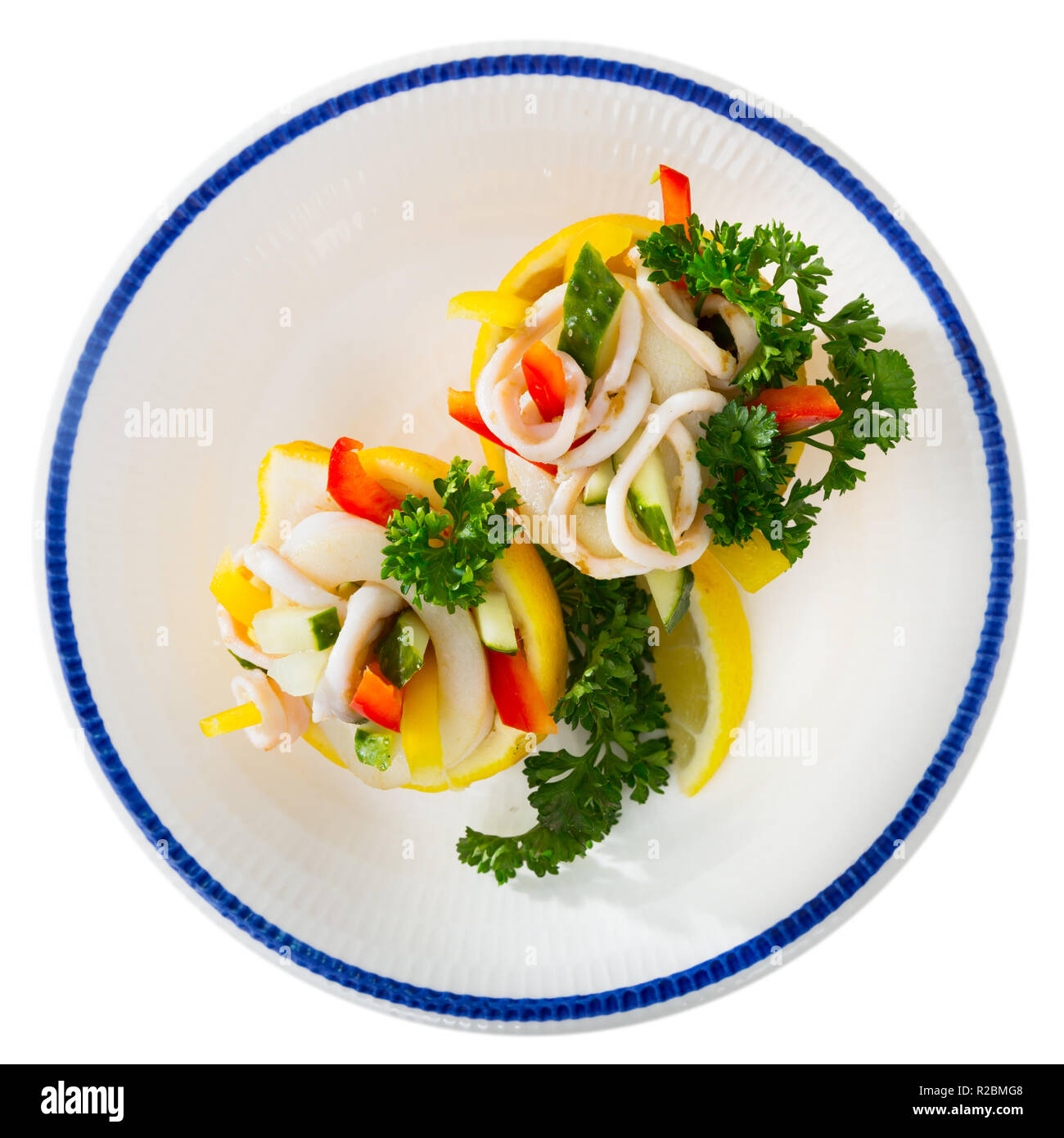 Tropischer Salat mit Calamari, Gurken, rote Paprika, in Zitrone Hälften mit Olivenöl und griechischer Joghurt serviert. Auf weissem Hintergrund Stockfoto