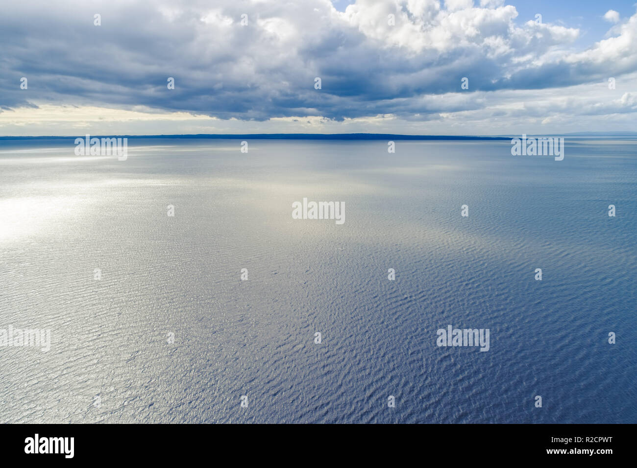 Kleine Flecken des Landes am Horizont mit Wolken über dem Wasser - Luftbild Landschaft Stockfoto