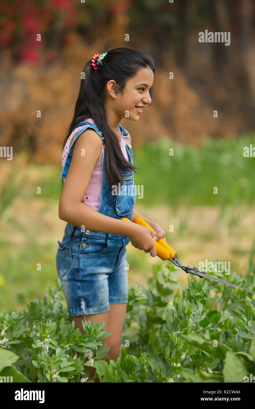 Junge Mädchen schneiden von Pflanzen im Garten mit einer Hecke Scherung oder Gartenarbeit Schere. Stockfoto