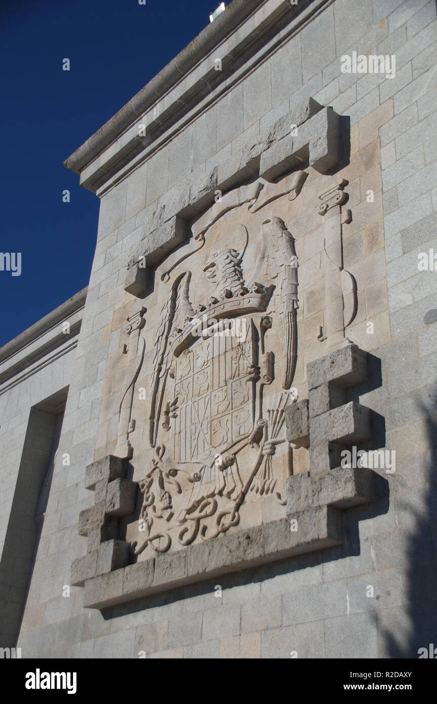 04 Oktober 2018, Spanien, El Escorial: Ein großes Wappen aus der Franco Zeitraum hängt am Denkmal im Valle de los Caídos (Tal der Gefallenen), wo sich das Grab des Diktators Francisco Franco befindet. Drei Tage nach seinem Tod, wurde er in der Basilika am 23. November 1975 begraben. Das Mausoleum, das in den Felsen von 20.000 Zwangsarbeiter zwischen 1940 und 1959 vertrieben wurde, gilt als eine der größten der Welt. Es ist das wichtigste architektonische Symbol der Franco-diktatur. Neben der Basilika, die Gebeine von mehr als 30.000 Soldaten, die starben während der spanischen Civi Stockfoto
