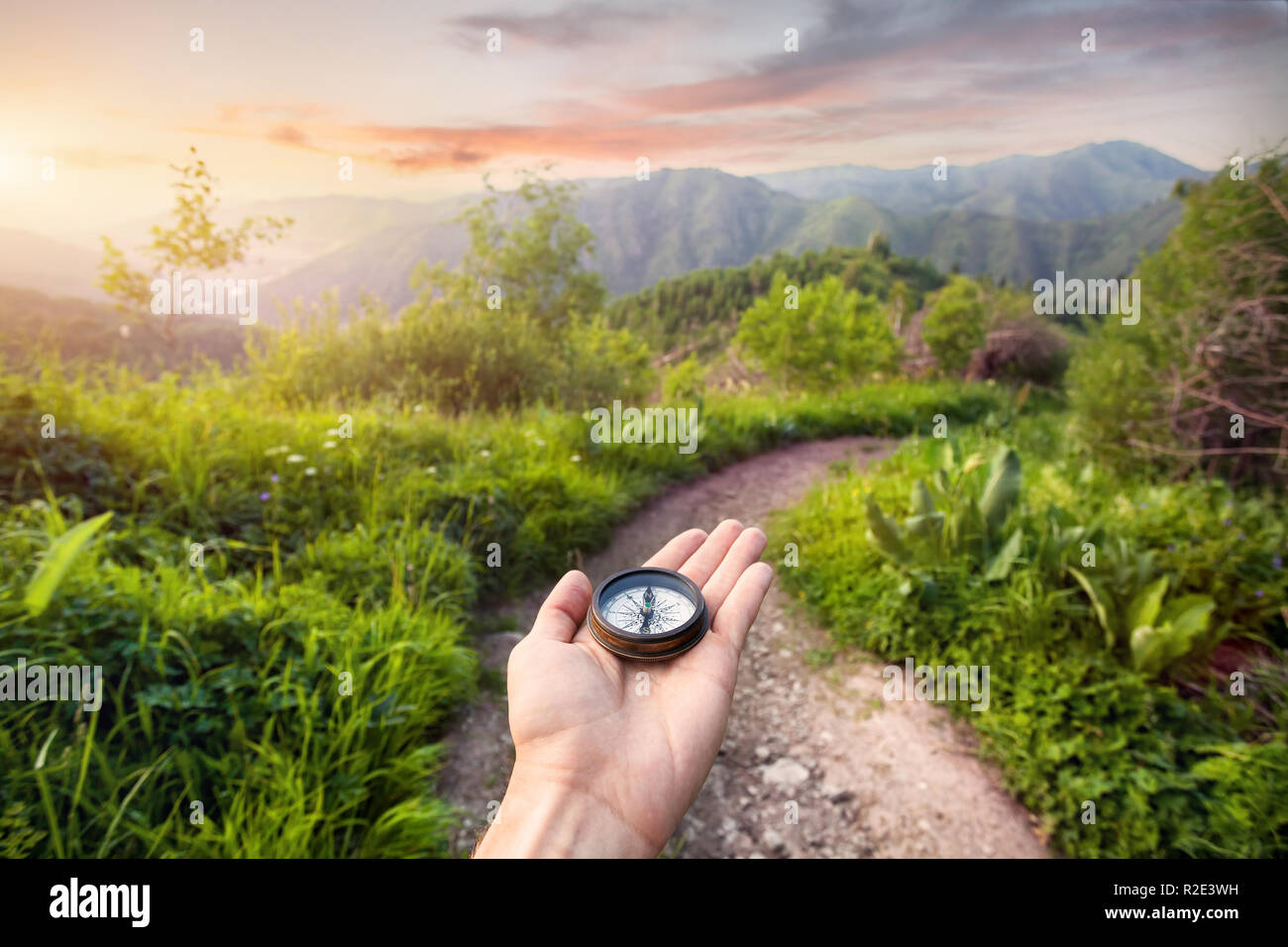 Hand mit Kompass am Berg Straße bei Sonnenuntergang Himmel in Kasachstan und Zentralasien Stockfoto