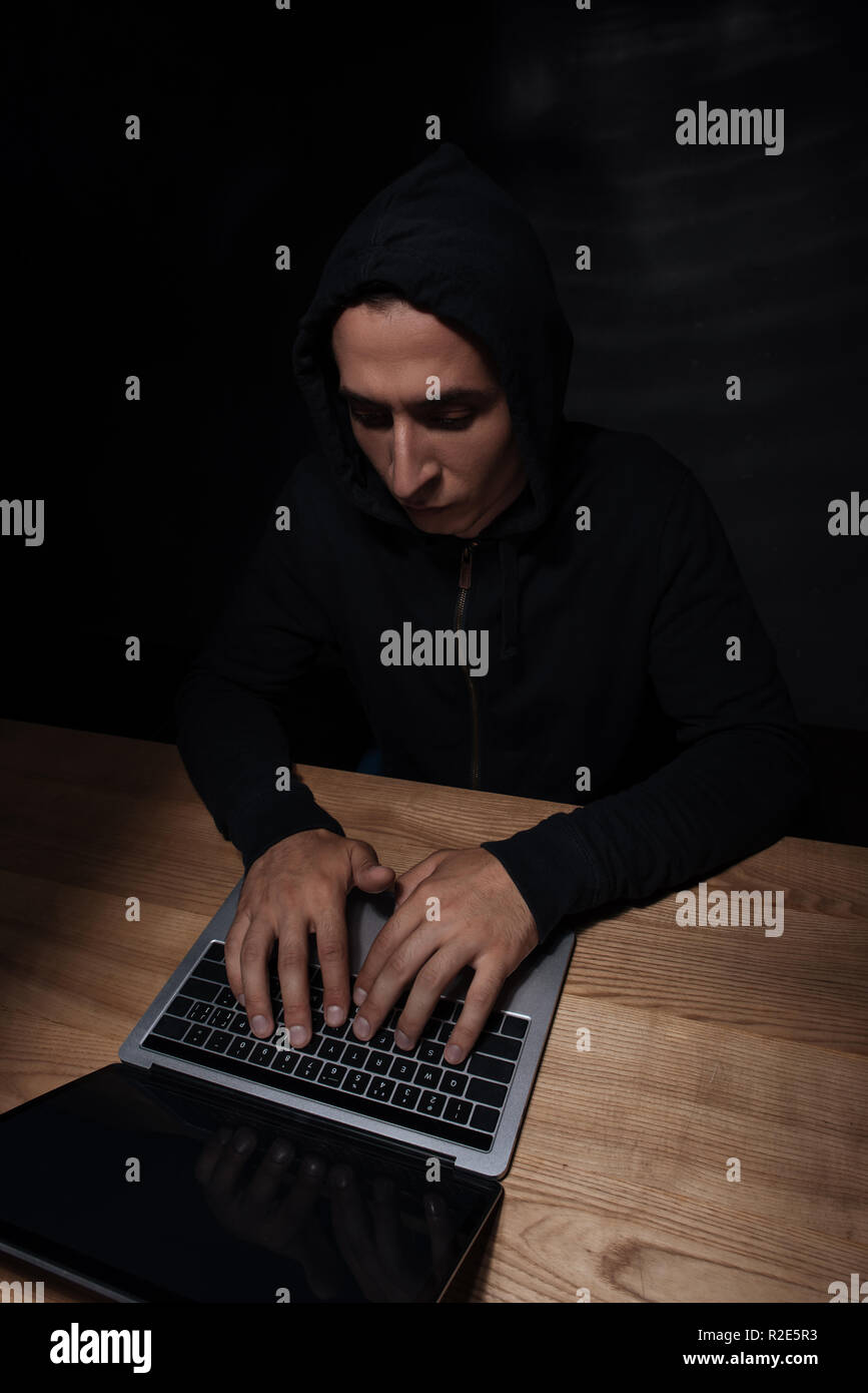 Mit Laptop an der hölzernen Tischplatte hacker konzentriert, cuber Sicherheitskonzept Stockfoto