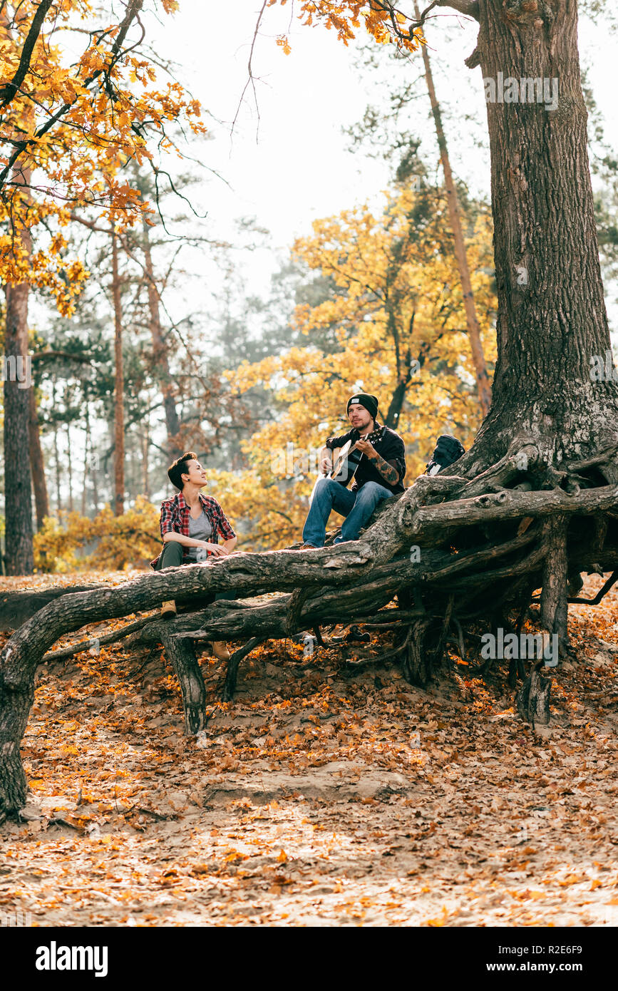 Erwachsene Frau und Mann sitzt auf Baum im Wald auf autumal Hintergrund Stockfoto