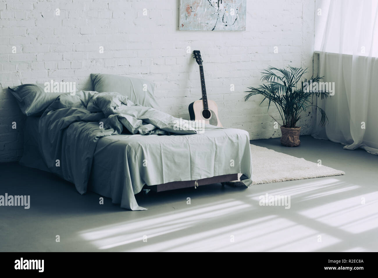 Innenraum der modernen Schlafzimmer mit Gitarre und Zimmerpflanze Stockfoto