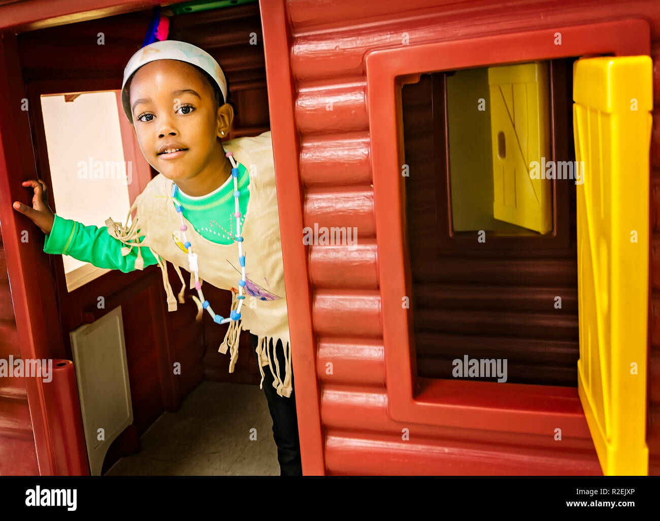 Ein Pre-school student Einblicke aus einer Kabine Playhouse anmelden, während in einem Indianer Kostüm, November 21, 2012, in Columbus, Mississippi gekleidet. Stockfoto