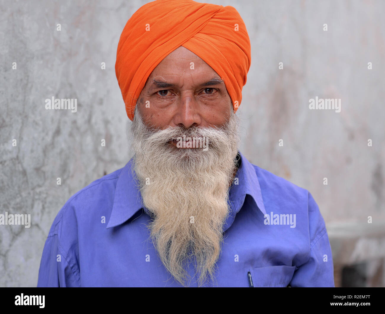 Im mittleren Alter indischer Sikh Mann mit orange traditionellen Turban (Dastar) posiert für die Kamera. Stockfoto