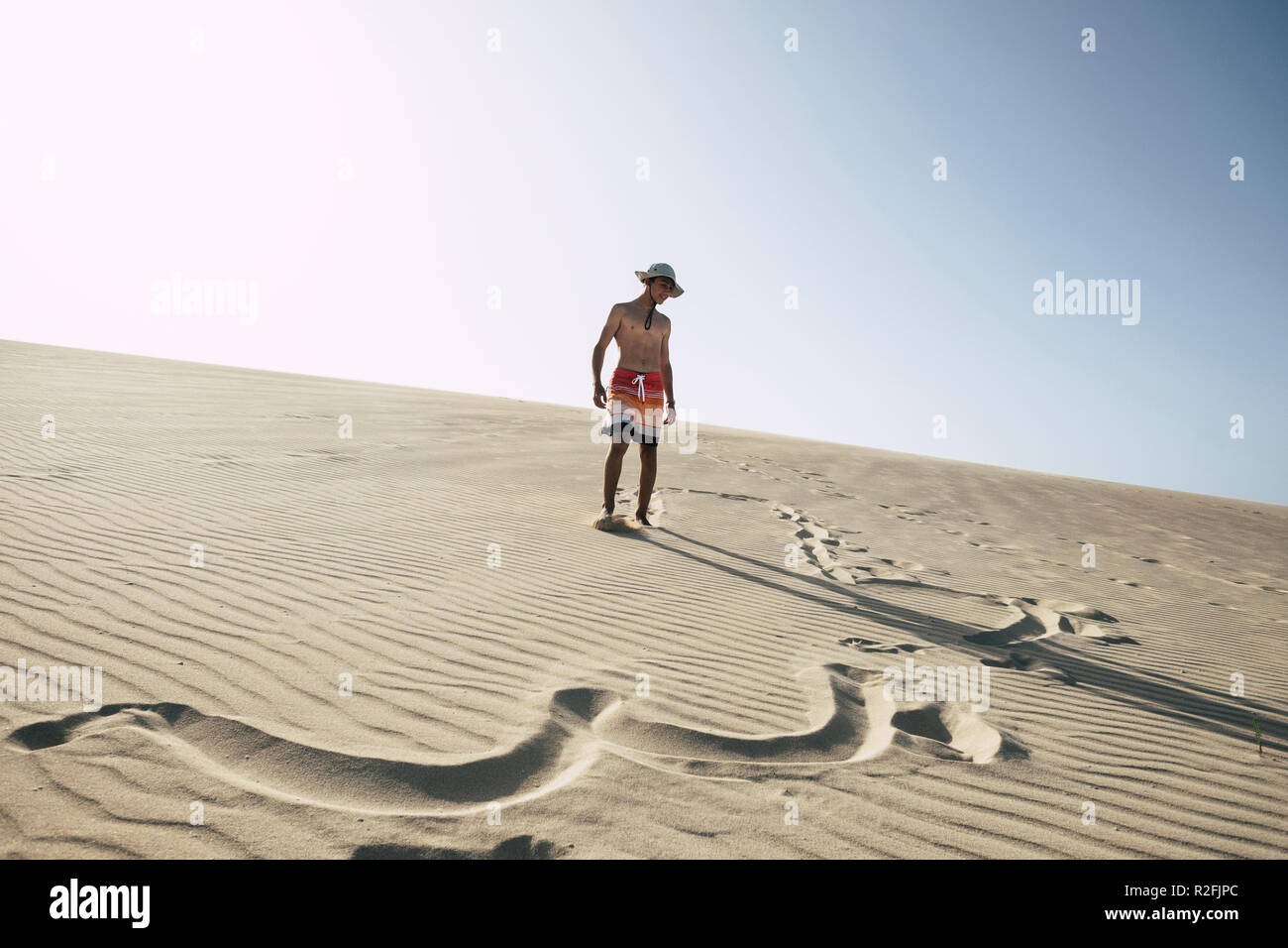 In Glück mitten in der Wüste mit Sand Dünen verloren. Junge glückliche junge Teenager genießen Ferien am Strand. klaren blauen Himmel im Hintergrund. Badeanzüge und Zeichen in den Sand. Sommer Tag Stockfoto