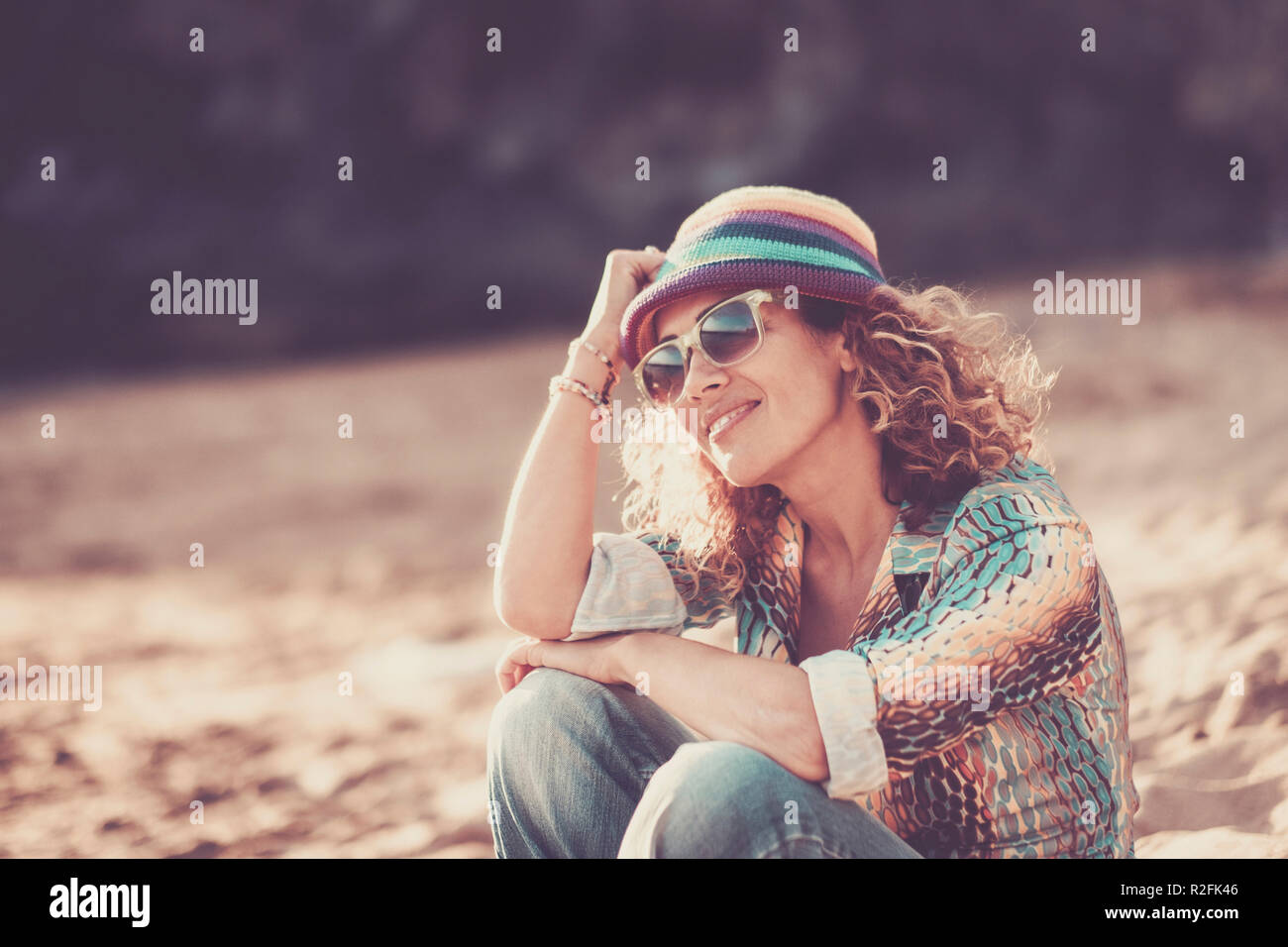 Gerne schöne fröhliche kaukasische Frau mittleren Alters sitzen am Strand und genießen den Sommer. Lächeln und Entspannen nach der Arbeit. Urlaub und Reisen Konzept mit attraktiven und alter Leute mit bunten Lebensstil Stockfoto