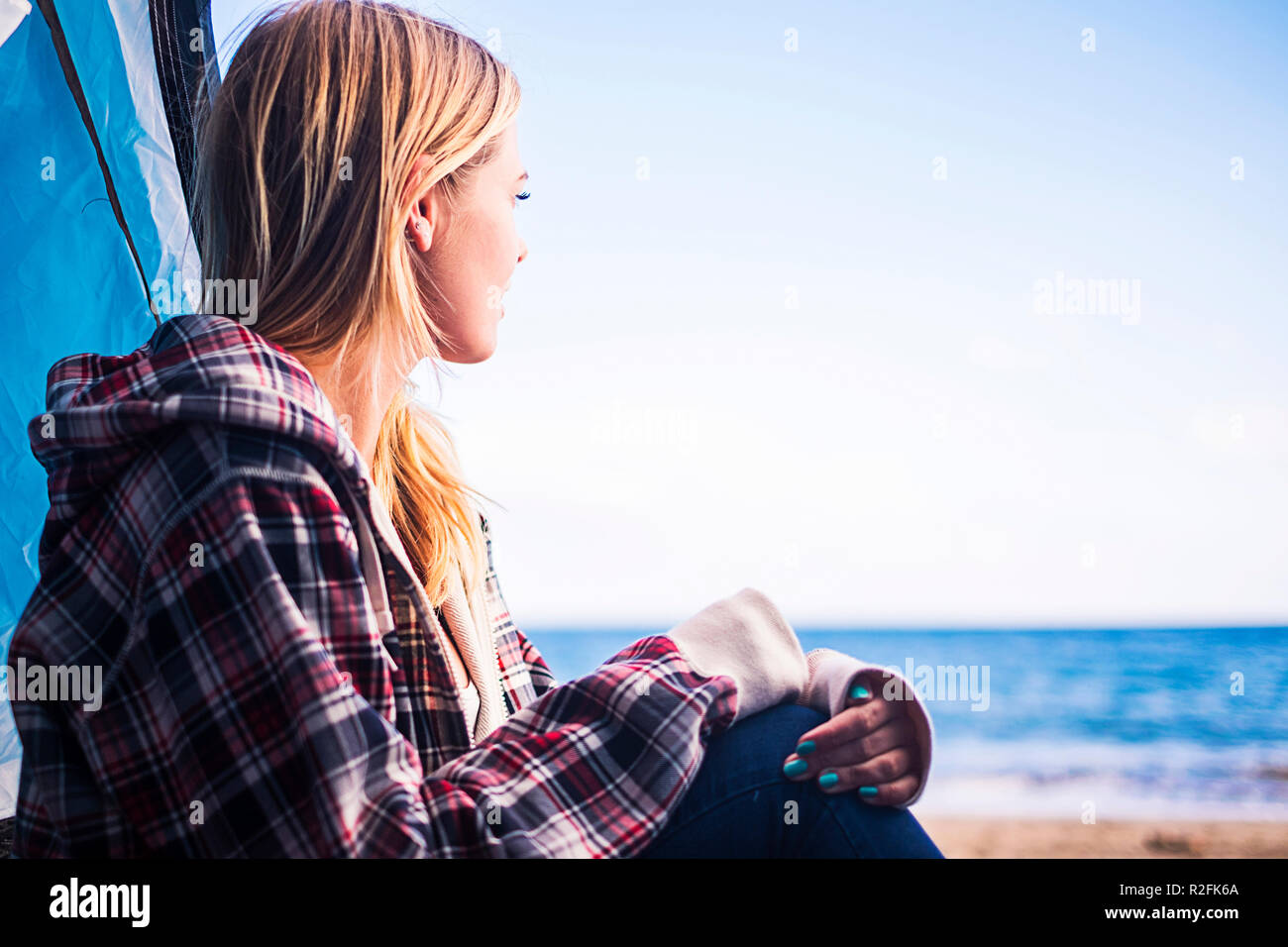 Alternative Lebens- und Ferienhäuser Konzept für Blonde süße Mädchen sitzen unten am Meer an der Tür Ihres Zeltes. Teneriffa locetion. Stockfoto Alternative Lebens- und Ferienhäuser Konzept für Blonde süße Mädchen sitzen unten am Meer an der Tür Ihres Zeltes. Teneriffa locetion. Stockfoto