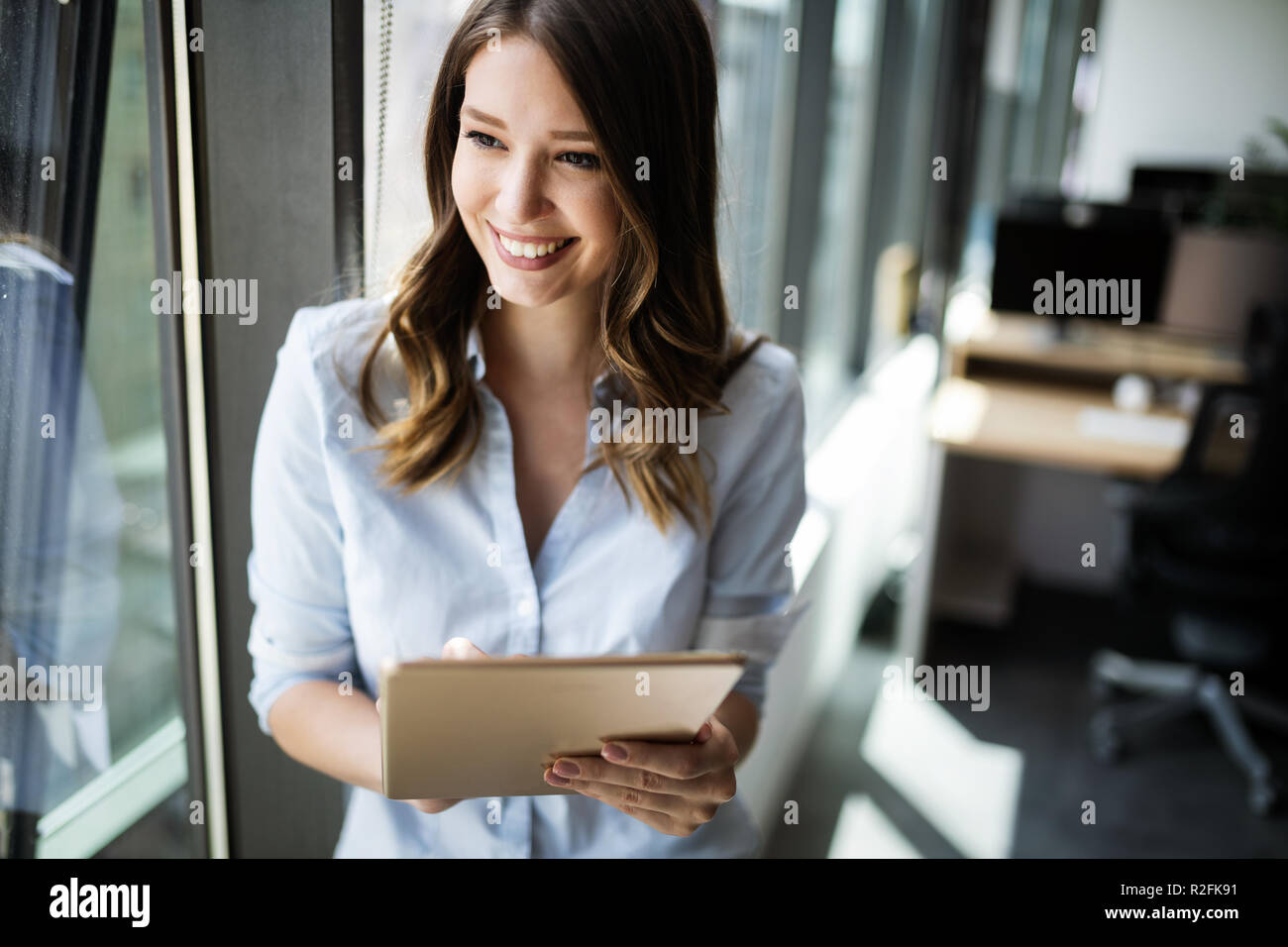 Attraktive Geschäftsfrau mit einem digitalen Tablet beim Stehen vor der Fenster Stockfoto