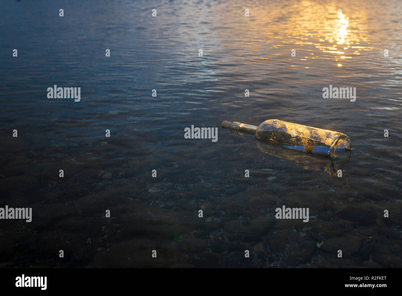 Glasfläschchen mit einer Nachricht über das Seil von der See geschlossen und fand an einem Kieselstrand Stockfoto