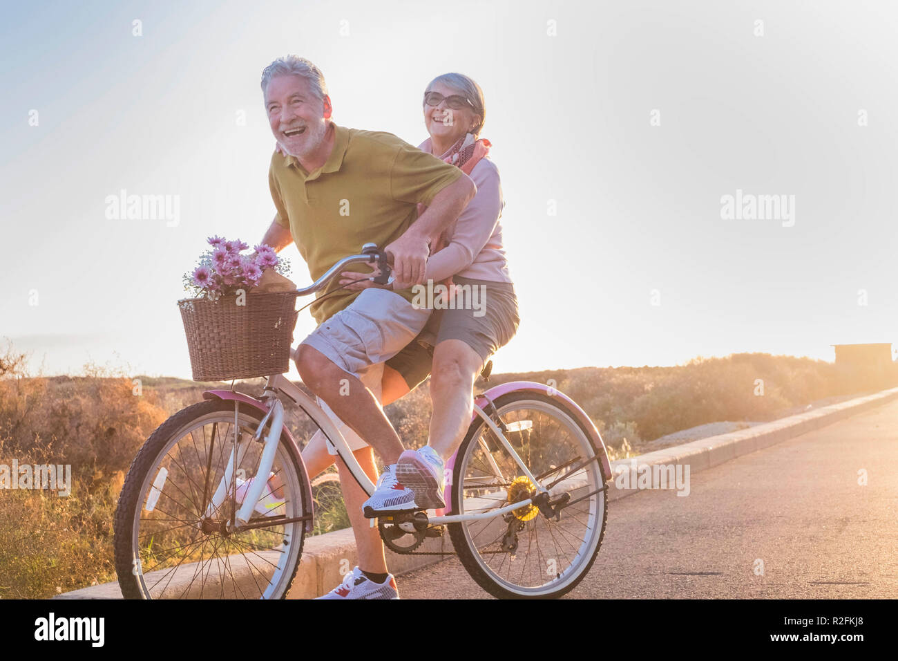 Freude und Glück für Erwachsene Ehepaar starten und Spaß haben, die auf demselben Bike Outdoor Aktivität mit Sun Hintergrundbeleuchtung auf dem Hintergrund. klares und helles Bild für Lächeln und Lachen Menschen. lifestyle Konzept genießen. Stockfoto
