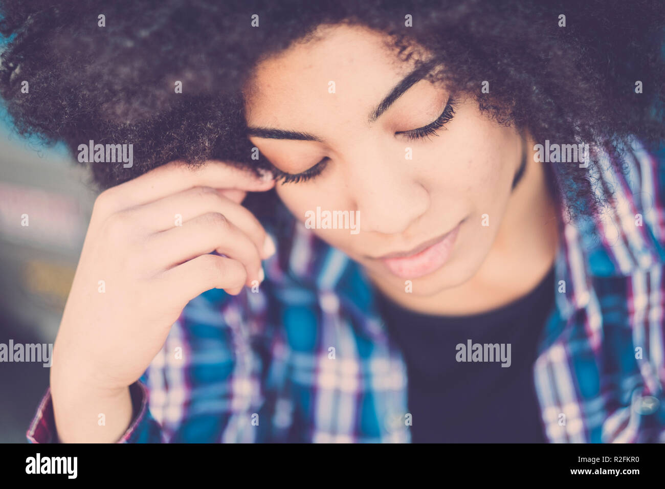 Nahaufnahme, Porträt einer wunderschönen schwarzen Frau nachdenklich mit geschlossenen Augen und suchen nach unten. oben Sicht für Zärtlichkeit und Einsamkeit Konzept. attraktives Mädchen mit afrikanischem Haar. Stockfoto