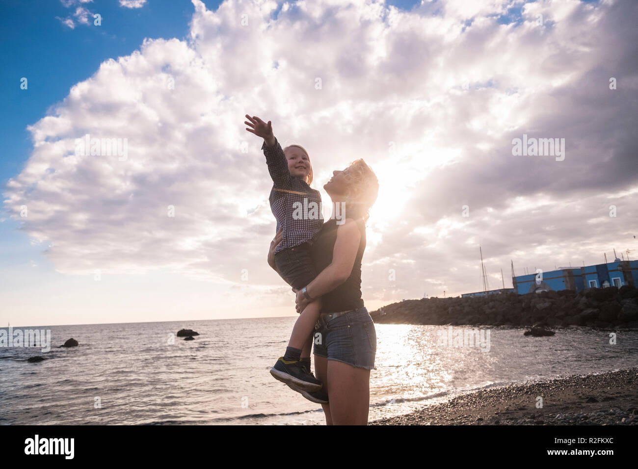 Freude und Glück Konzept mit Liebe zwischen kaukasischen Frau und junge Mutter und Sohn umarmen und spielen in Urlaub Freizeitaktivitäten Kalendertage mit Sonnenuntergang und Wolken im Hintergrund. Lifestyle für fröhliche Menschen Stockfoto