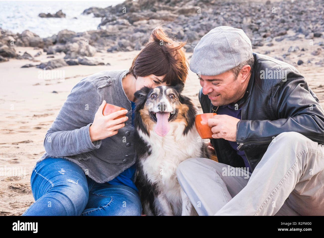 Familie mit einem Border Collie Hund tun Pic Nic Aktivität am Strand in Ferien, Sommer Lifestyle mit Freunden Konzept. im alten Stil und vintage Filter. Kaffee Pause Zeit Stockfoto