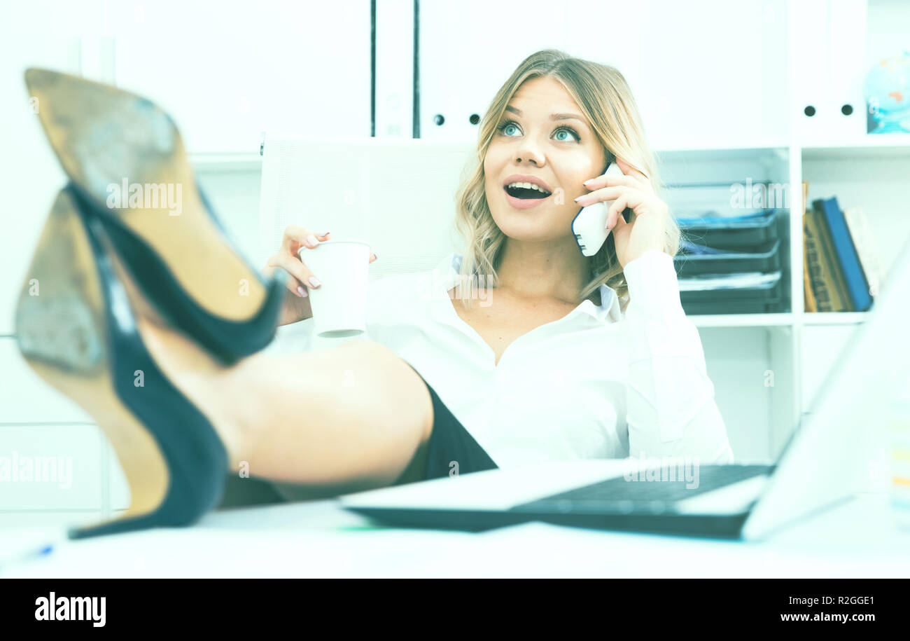 Sorglose Mädchen in Business Kleidung setzt ihre Füße auf dem Tisch und am Telefon sprechen Stockfoto