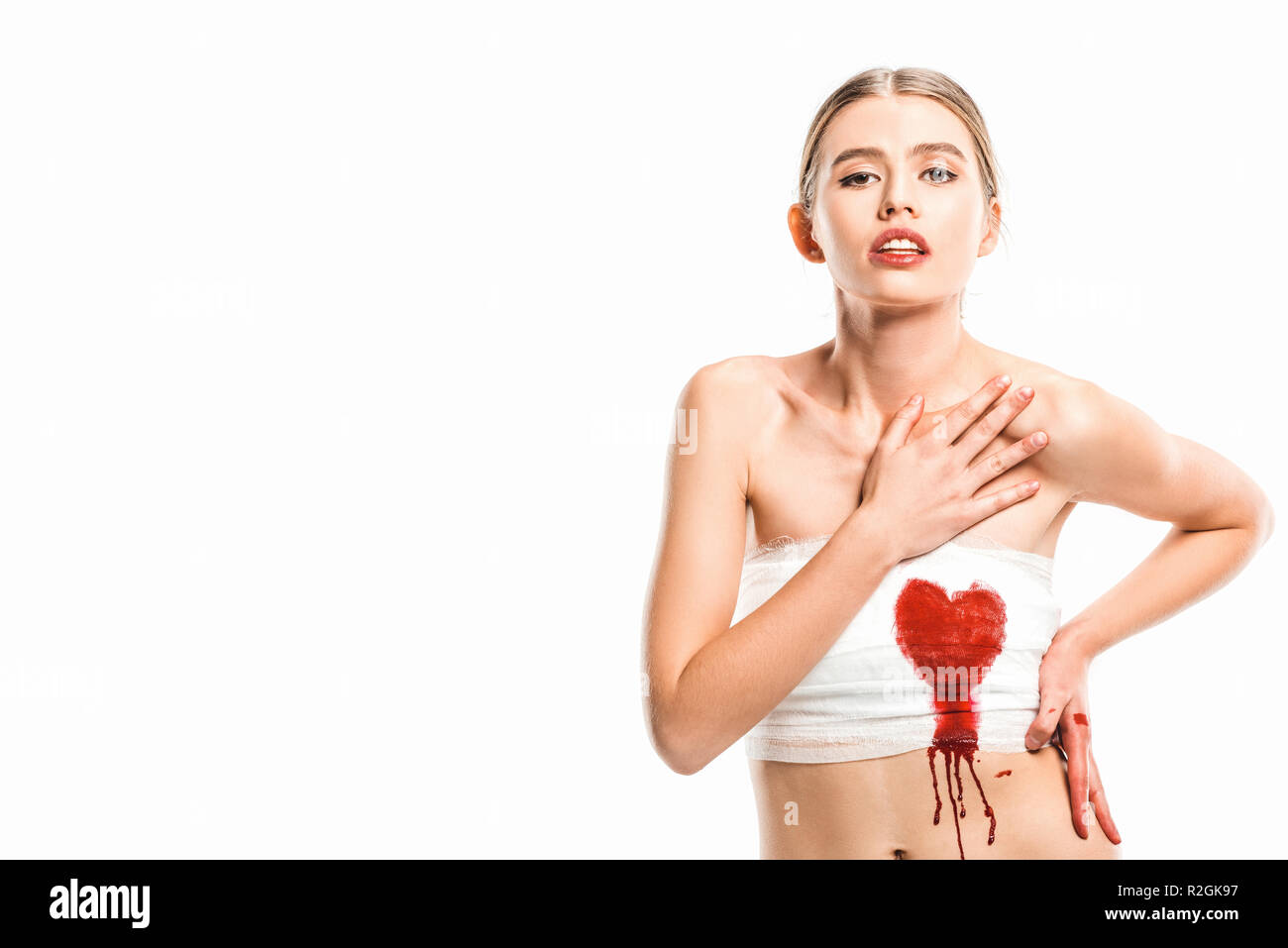 Erwachsene Frau in Bandagen mit blutigen Herzen isoliert auf weißem Stockfoto