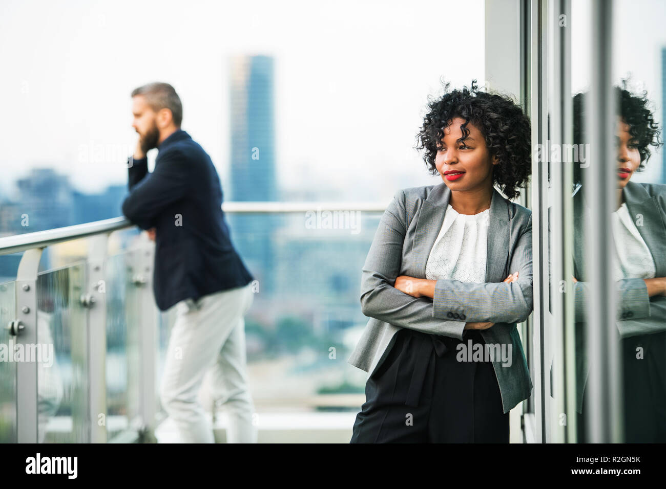 Das Porträt einer Geschäftsfrau, die auf eine Terrasse, die Arme verschränkt. Stockfoto