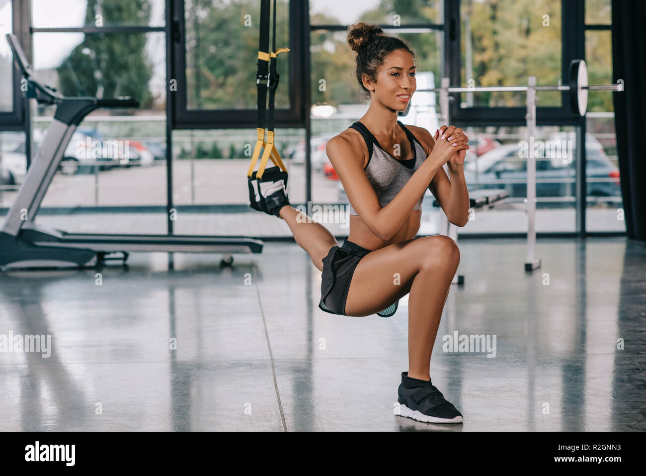 Schöne happy Sportlerin Ausübung auf Fitness Träger im Fitnessraum Stockfoto