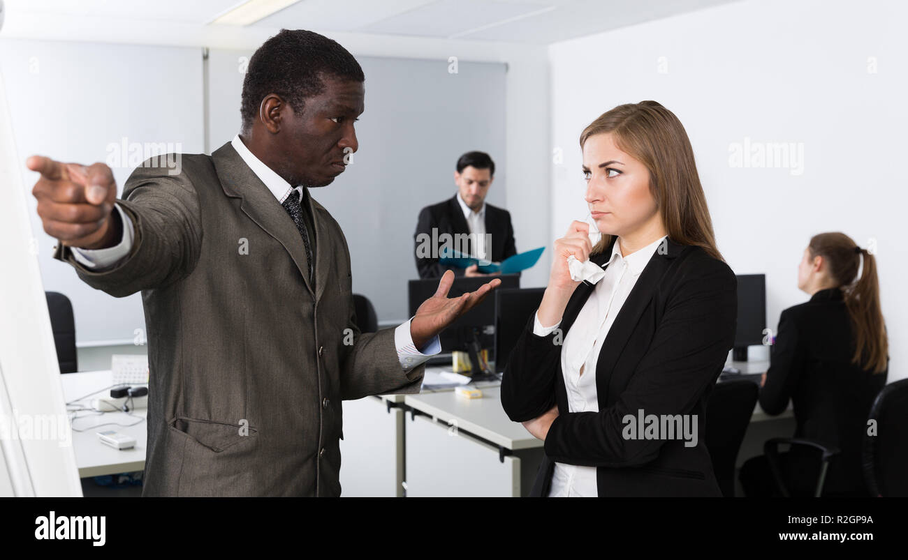 Zornigen Mann Chef pointinting zu vermisst in der Arbeit zu weiblicher Manager arbeiten im Büro Stockfoto