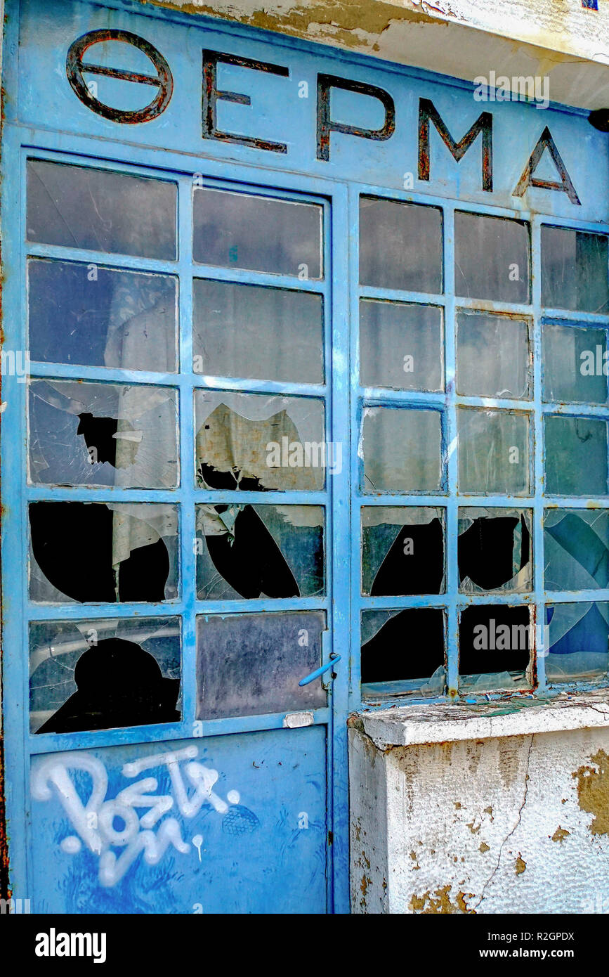 Verlassene und verfallene Store Front mit zerbrochenen Fensterscheiben. Wirtschaftliche Not und Depression. In Athen, Griechenland, fotografiert. Stockfoto