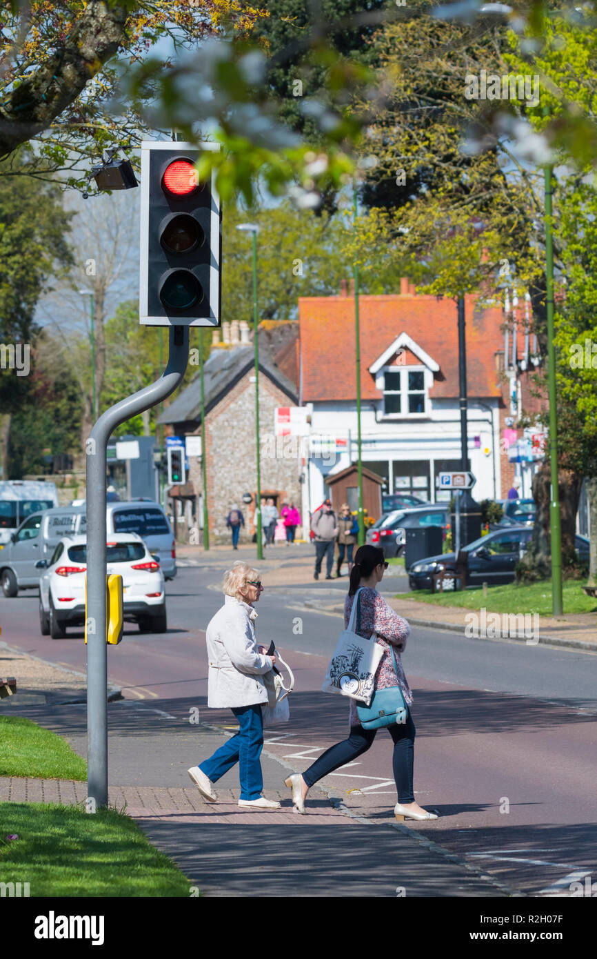 Menschen, die über ein papageientaucher Kreuzung während es zeigt ein rotes Licht für Fahrzeuge, die in einem britischen Stadt in Rustington, West Sussex, England, UK. Stockfoto