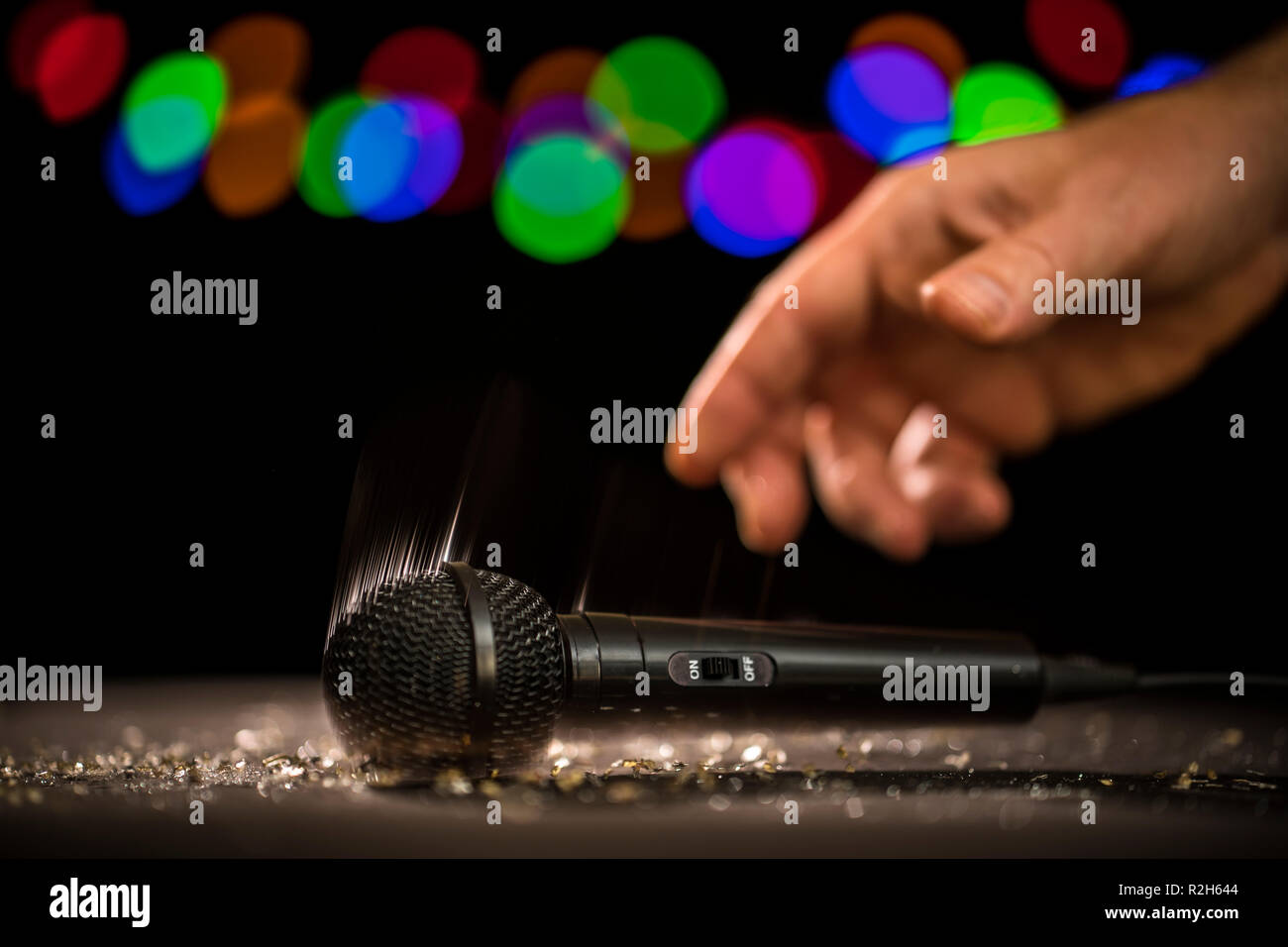 Mic Drop! Eine Hand fällt ein Mikrofon auf eine Bühne. Stockfoto