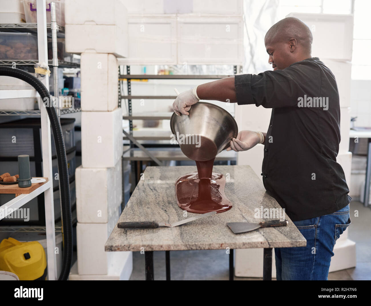 Arbeitnehmer gießen geschmolzene handwerklichen Schokolade heraus auf eine Fabrik Tabelle Stockfoto