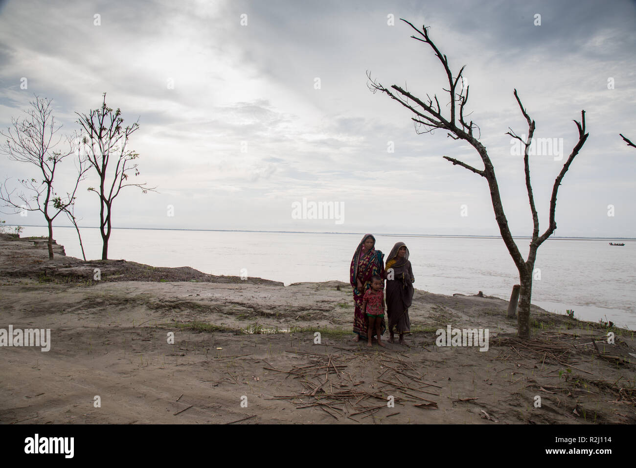 Von Lebensmitteln betroffene Familienmitglieder, die aufgrund von Flußerosion ihre Häuser verloren, posieren auf dem Ufer der Jamuna im Norden von Bangladesch Stockfoto