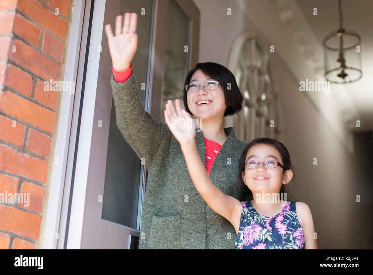 Mutter und Tochter winkt an der vorderen Tür Stockfoto