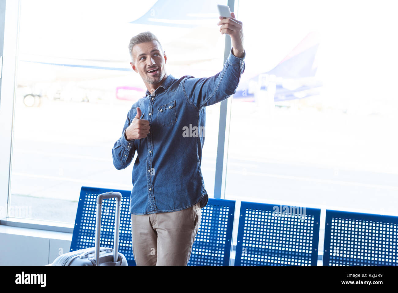 Menschen, die in den Flughafen Lächeln zeigen, Daumen hoch und unter selfie auf dem Smartphone Stockfoto