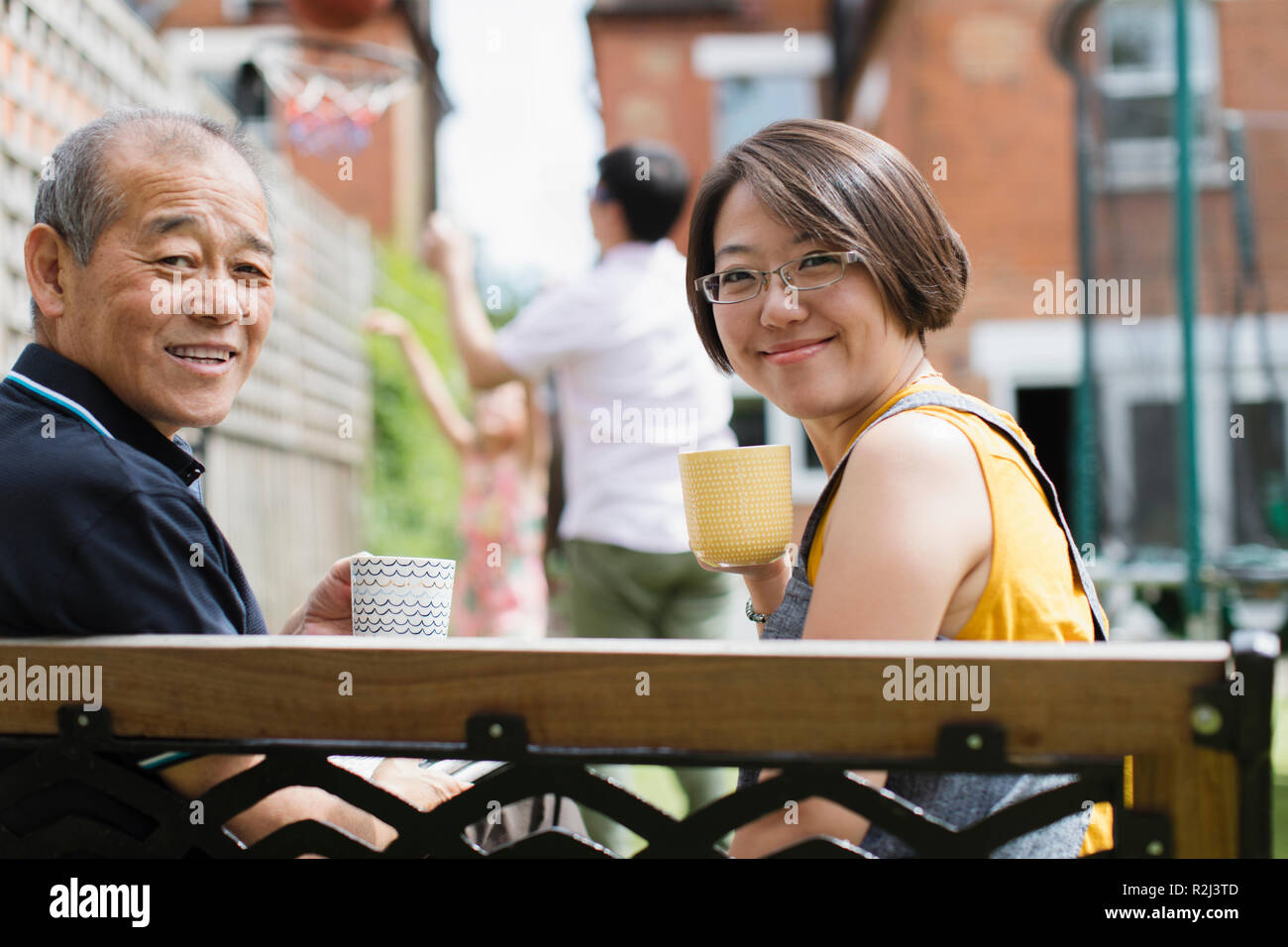 Portrait lächelnden Tochter und Vater trinkt Tee auf der Bank im Hof Stockfoto