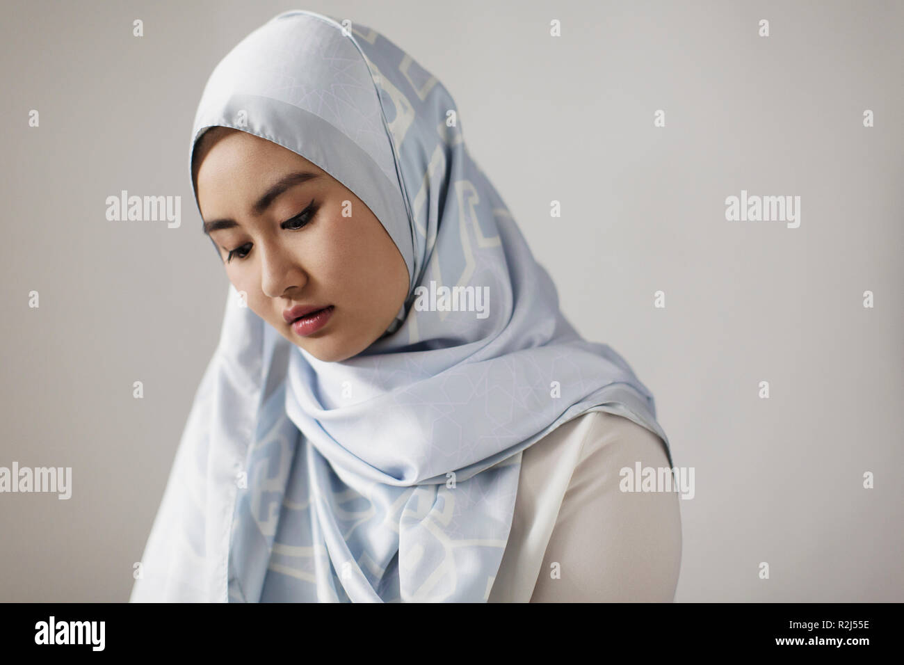 Ruhige junge Frau trägt blaue Seide hijab Stockfoto