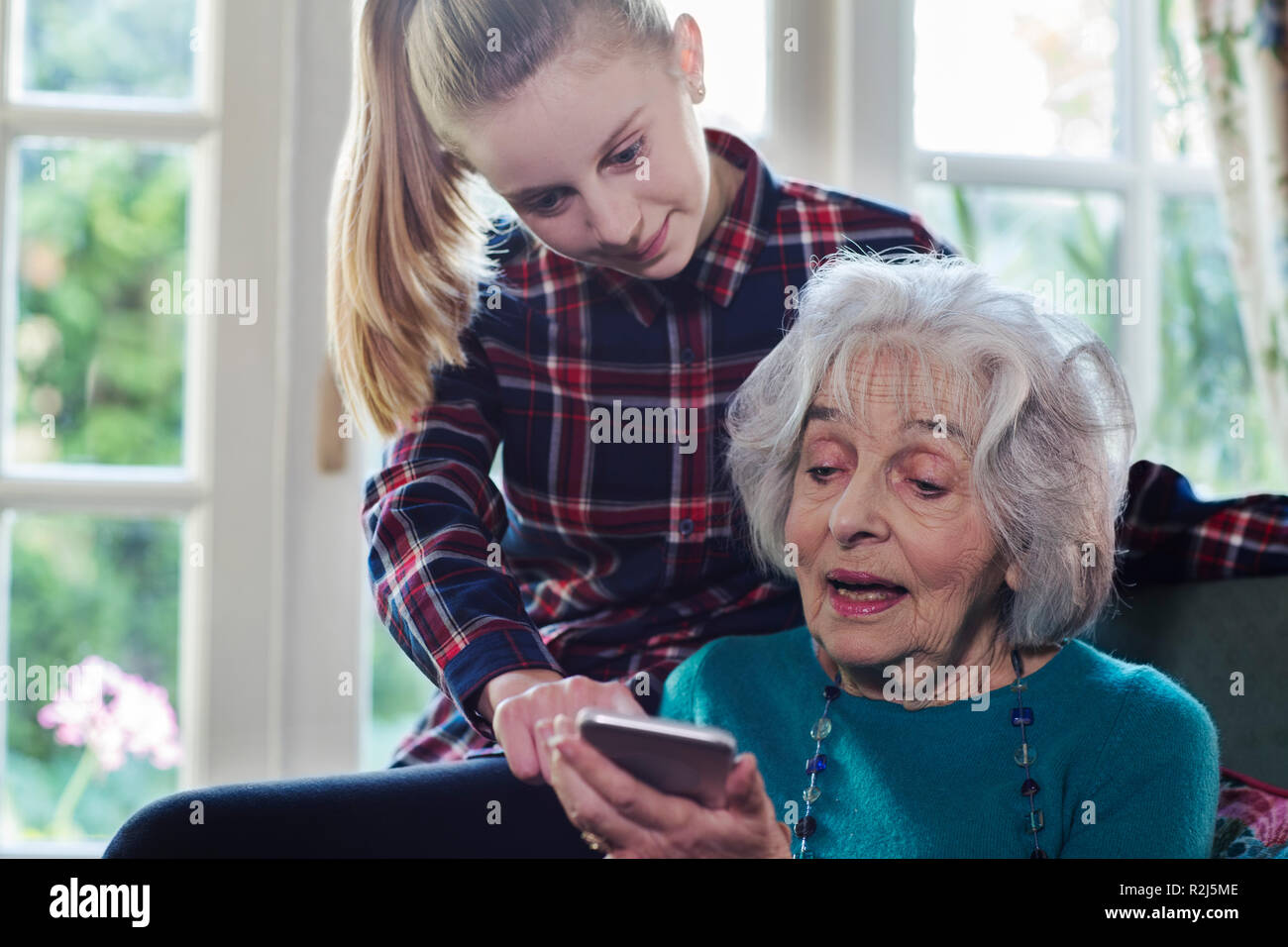 Teenager Enkelin zeigt Großmutter wie Nutzung Handy Stockfoto